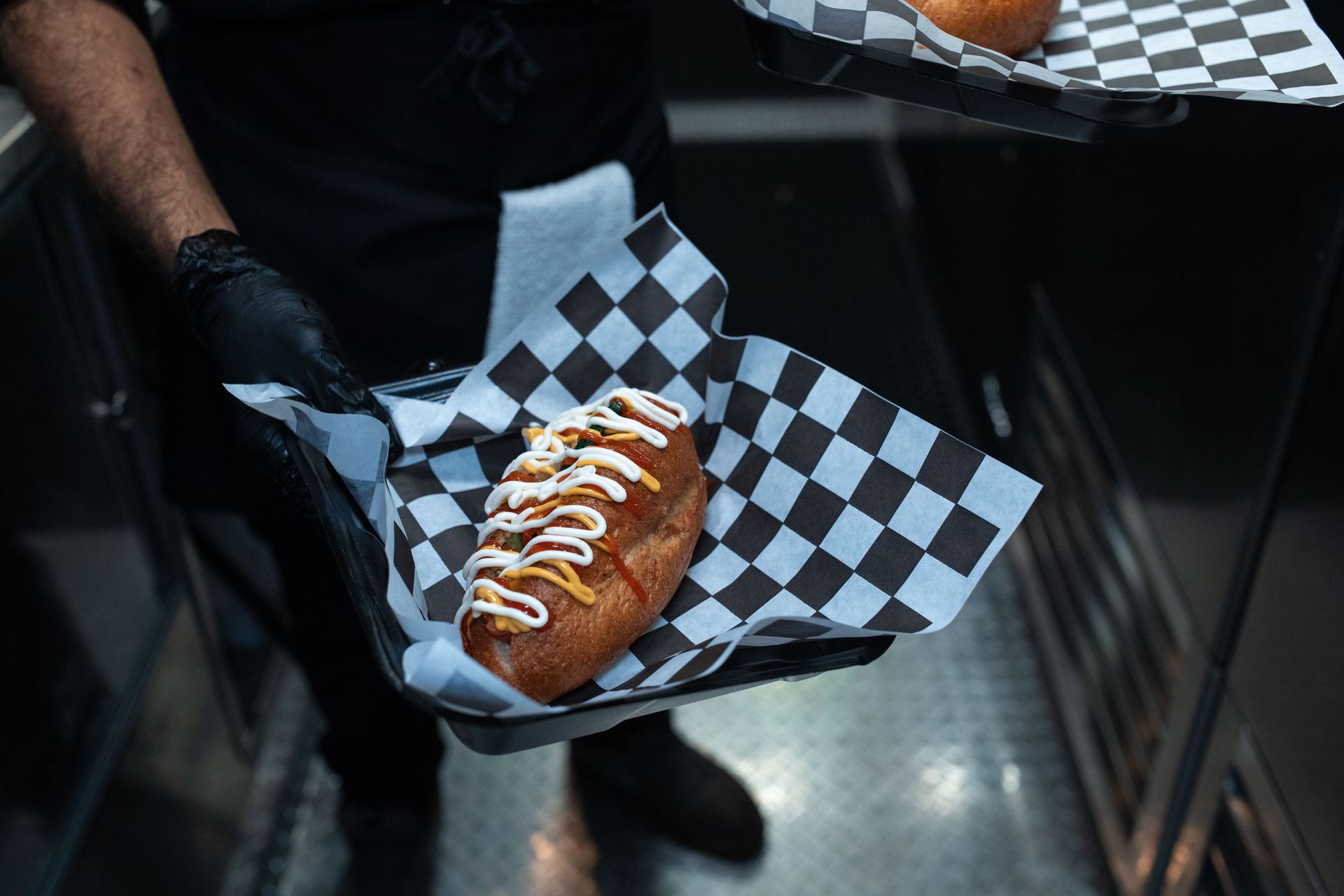 Delicious hot dog with toppings served in a commercial kitchen setting.