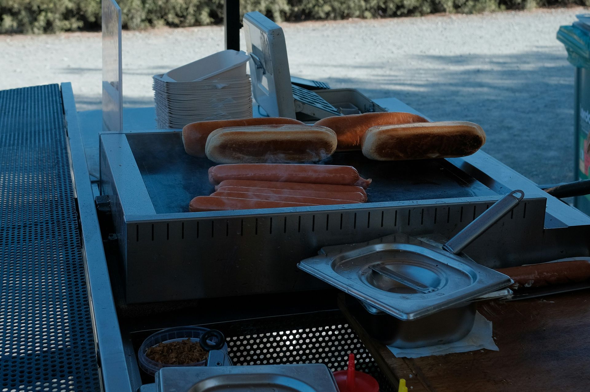 Hot dogs cooking on a flat top grill outdoors